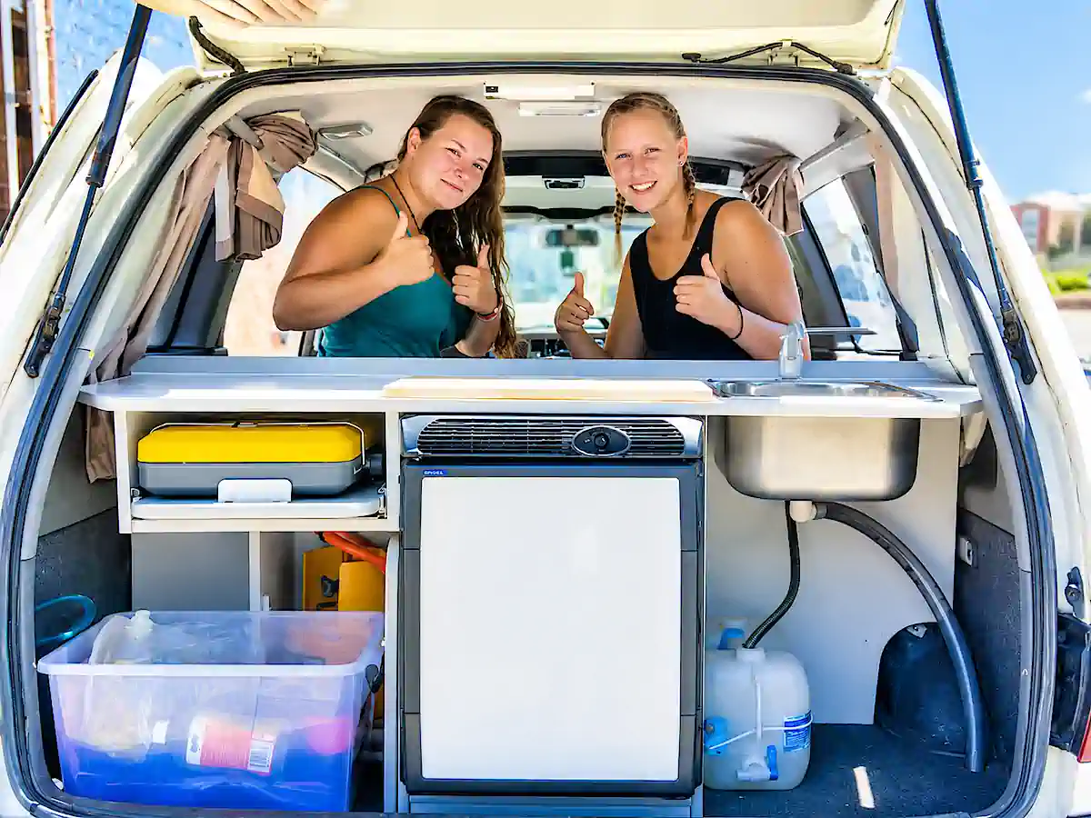 Backpacker Camper in Sydney kaufen – zwei Reisende mit ausgestatteter Heckküche
