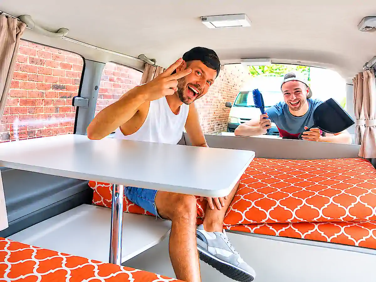 Backpacker Camper in Sydney kaufen – zwei Reisende im Wohnbereich mit Tisch und Sitzbänken