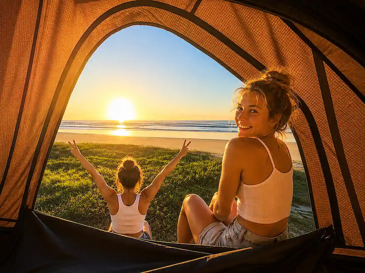 Reisende genießen den Sonnenuntergang am Strand aus ihrem Dachzelt in Australien